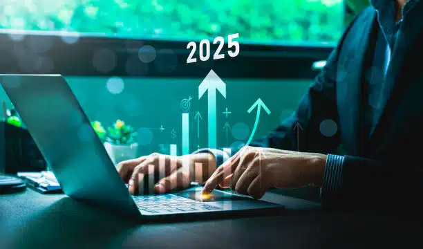 Businessman analyzing 2025 financial growth projections on a laptop with digital bar graphs and arrows